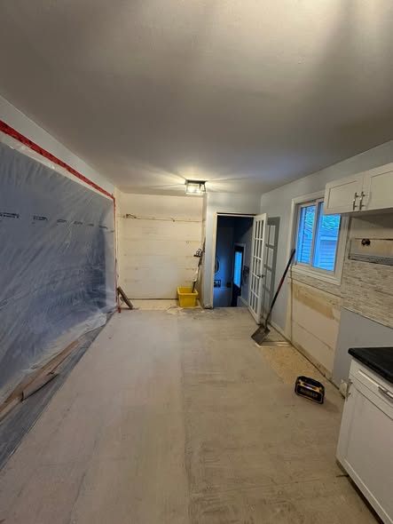 Kitchen renovation in progress, with flooring removed and a plastic dust barrier